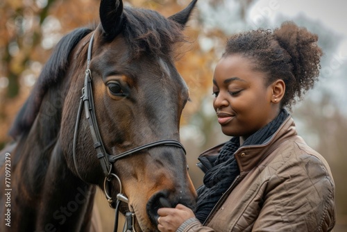 Tender moment between a plus-size African American woman and a horse in an autumn setting. © evgenia_lo