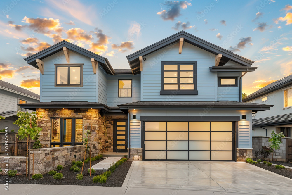 A luxurious modern residence with a two-car garage, framed by a soft powder blue siding and accented with natural stone wall trim for an elegant touch.
