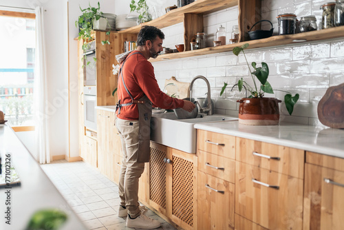 Man Washing Dishes in Modern Kitchen photo
