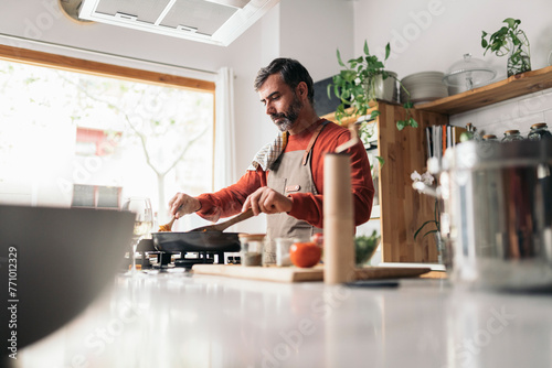 Joyful Man Cooking in a Sunny Kitchen photo