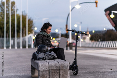 Entrepreneur networks on laptop strolling city with e-scooter photo