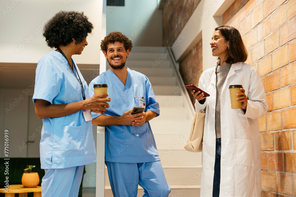 © BONNINSTUDIO/Stocksy - Doctors discussing project in hall