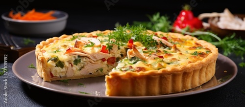 A savory quiche with a missing slice sits on a plate, a delicious baked goods dish made with ingredients like eggs, cheese, and vegetables, a classic comfort food in French cuisine