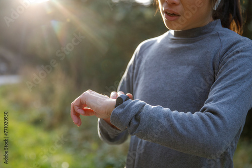 Sportswoman analyzing jogging track on smartwatch in sunlight photo