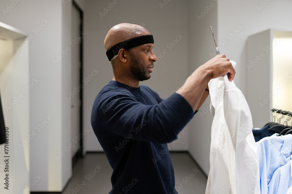 Man After Hair Graft Surgery Holding Shirt In Store Man After Hair Graft Surgery Holding Shirt In Store