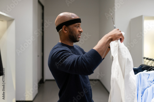 Man After Hair Graft Surgery Holding Shirt In Store photo