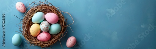 Easter Greetings: Pastel Painted Eggs in Bird Nest on Blue Table Texture Background - Celebration Banner or Greeting Card with Copy Space