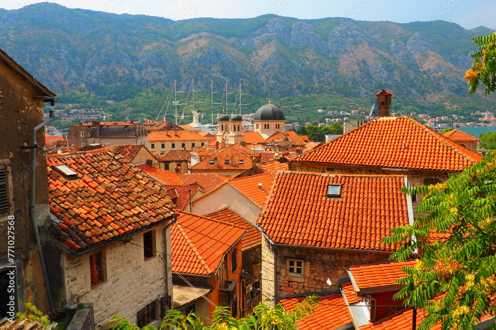 Kotor is a coastal city in Montenegro. Bay of Kotor. Red tiled roofs, mountain and chimneys of a tourist ship. Excursions and tourism. Cathedral of Saint Tryphon. Medieval old towns in the Adriatic
