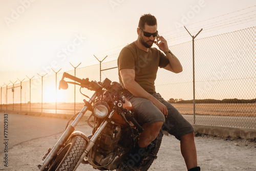 A man talks on the phone sitting on his motorcycle on a road photo