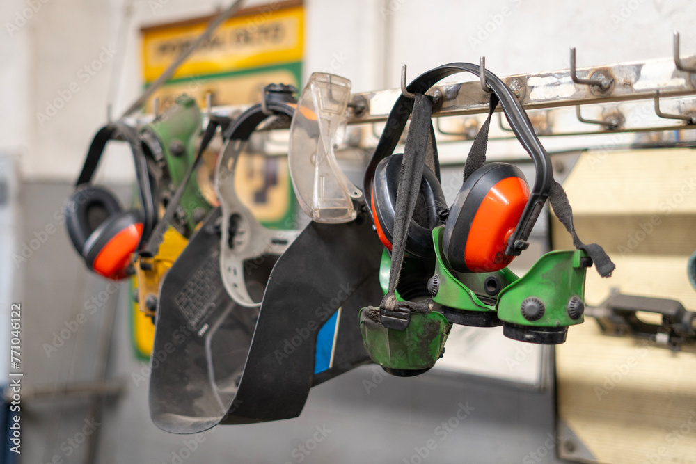 Welding helmets, protective glasses, ear protection hung in a row in a welding workshop Welding helmets, protective glasses, ear protection hung in a row in a welding workshop