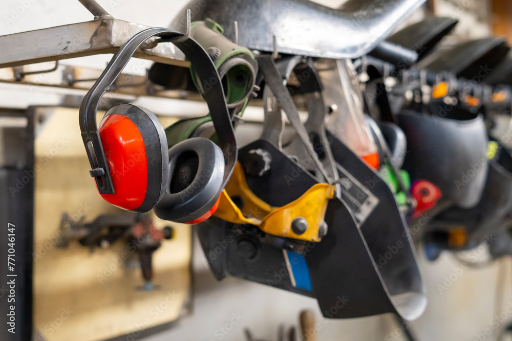 Welding helmets, protective glasses, ear protection hung in a row in a welding workshop Welding helmets, protective glasses, ear protection hung in a row in a welding workshop