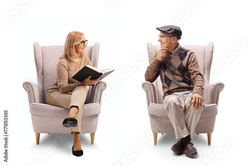 Mature woman holding a book and talking to a man seated in an armchair