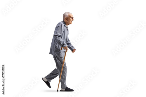 Full length profile shot of a en elderly man in pajamas walking with a cane