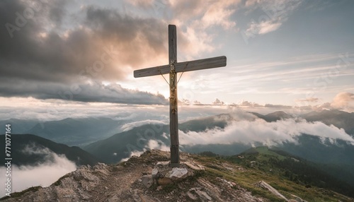 wooden cross on the top of the mountain with clouds on the background