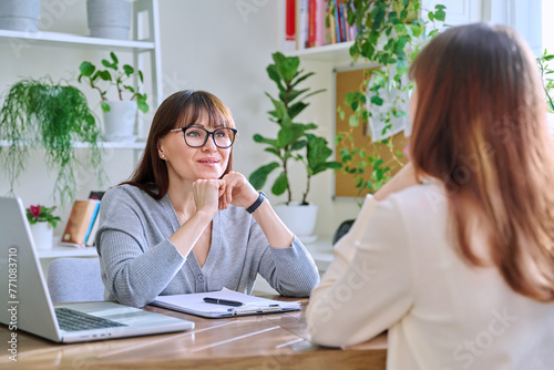 Middle-aged female psychologist, counselor working with young woman patient photo