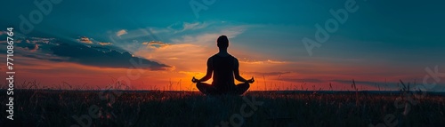A silhouette of a person meditating at dawn © Naret