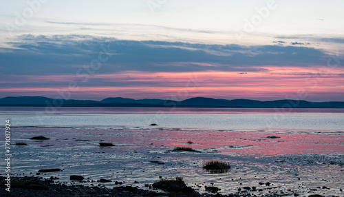 A stunning sunset over the St. Lawrence River near Rivière du Loup, Quebec, paints the sky red, mirrored flawlessly in the water below.