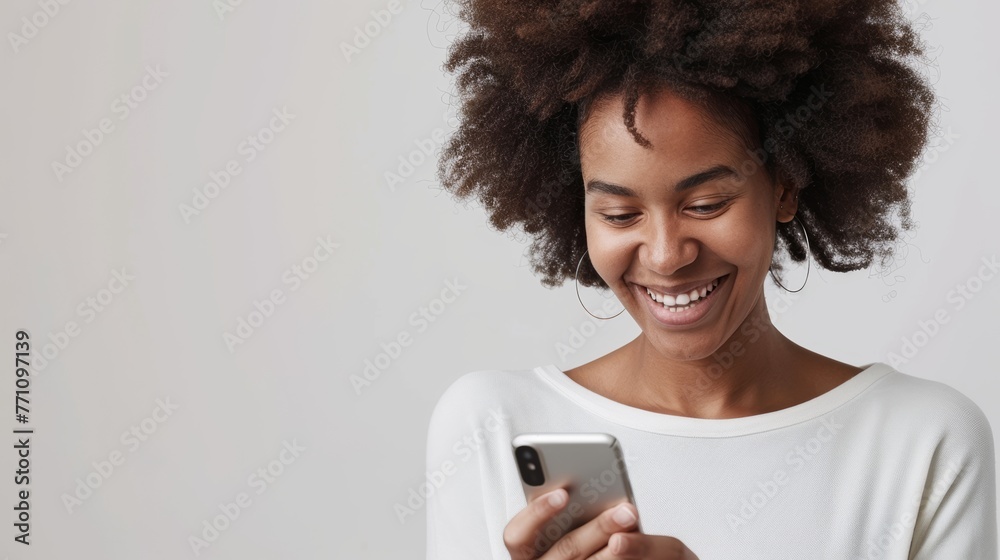 An African American woman grins while using her smartphone, evoking the pleasure of digital connectivity in everyday life - obrazy, fototapety, plakaty 