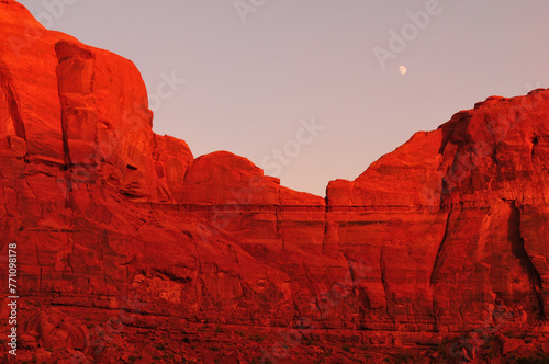 The moon and the sunset-lit sandstone cliffs of Monument Valley Navajo Tribal Park, Utah - Arizona state border, USA.