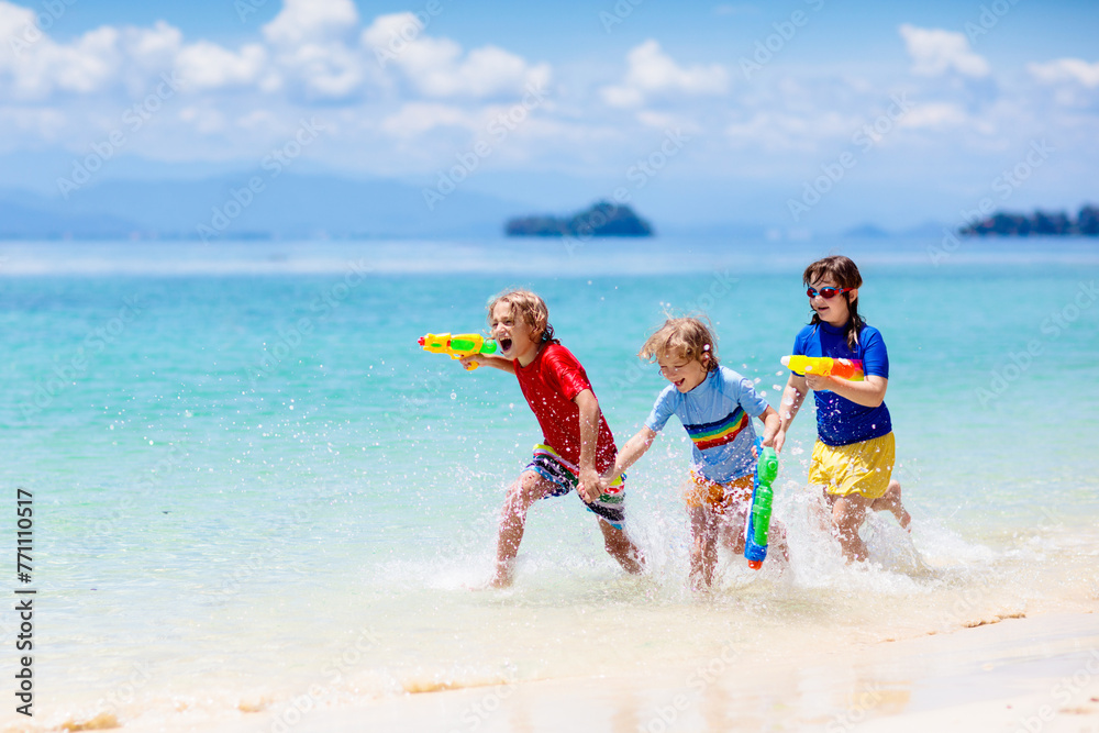 Child with toy water gun. Kids vacation beach fun. - obrazy, fototapety, plakaty 