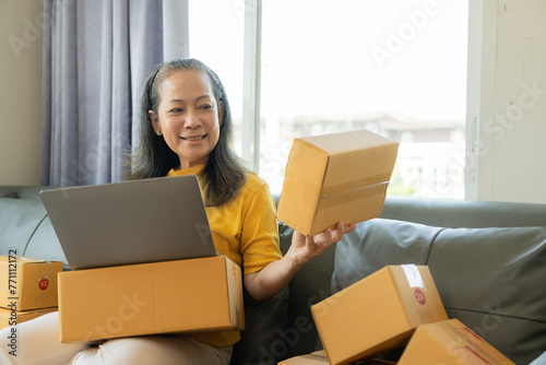 Happy mature businesswoman, small business owner in warehouse office There are parcel boxes piled up in the back, retail stores, individual entrepreneurs. Selling products online, SME business idea