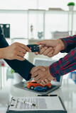 Car business, car sales, deals, gestures and concepts of close-up dealer people giving keys to new owner and shaking hands in office at table, close-up photo