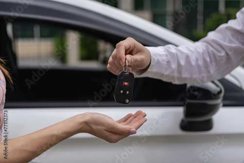 A young man receives keys from a car salesman. After agreeing to a lease or sale contract, buying a car and finance concept, close-up image