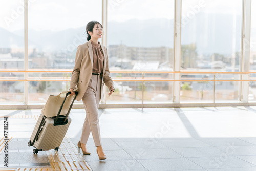 空港・駅・ビル・公共交通施設でスーツケースを持って歩くビジネスウーマン（海外出張・徒歩）
 photo