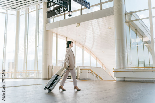 空港・駅・ビル・公共交通施設でスーツケースを持って歩くビジネスウーマン（海外出張・徒歩）
 photo