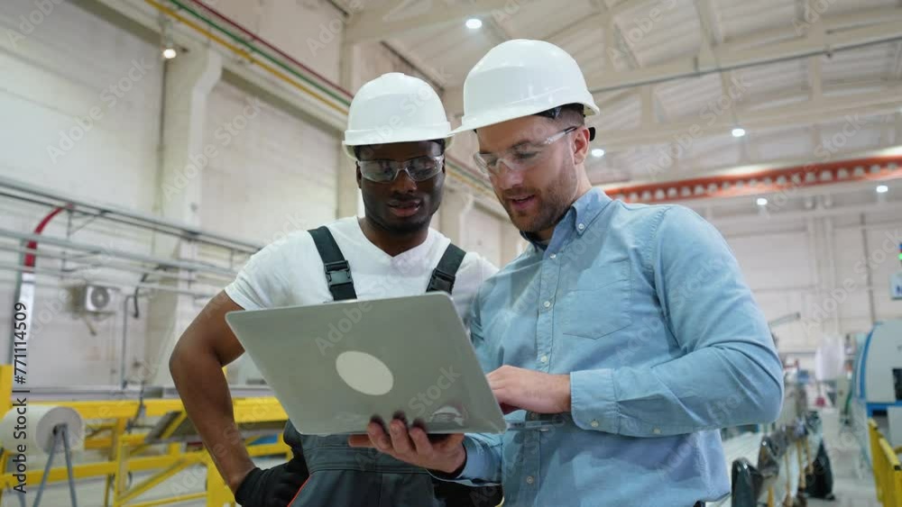 Supervisor and manual worker using laptop in heavy industry Supervisor and manual worker using laptop in heavy industry