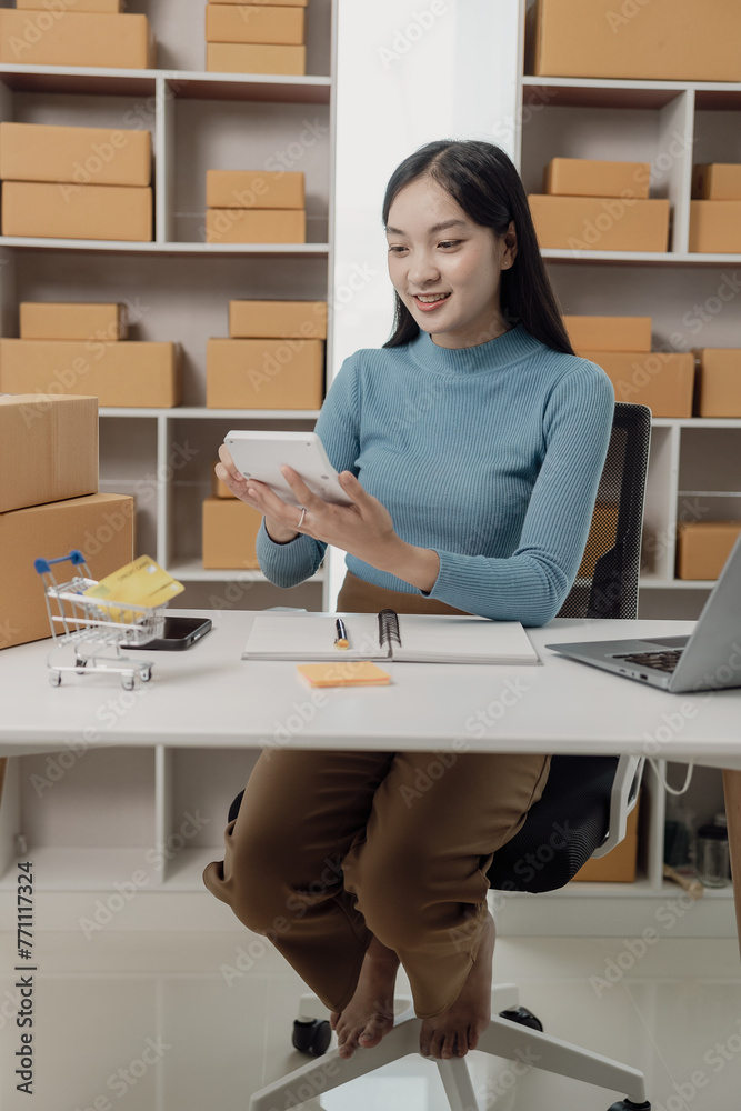 Postal parcel. Online sale. SME startup concept. Independent Asian woman small business entrepreneur wearing apron using laptop and box to order food online. SME business vertical image Postal parcel. Online sale. SME startup concept. Independent Asian woman small business entrepreneur wearing apron using laptop and box to order food online. SME business vertical image