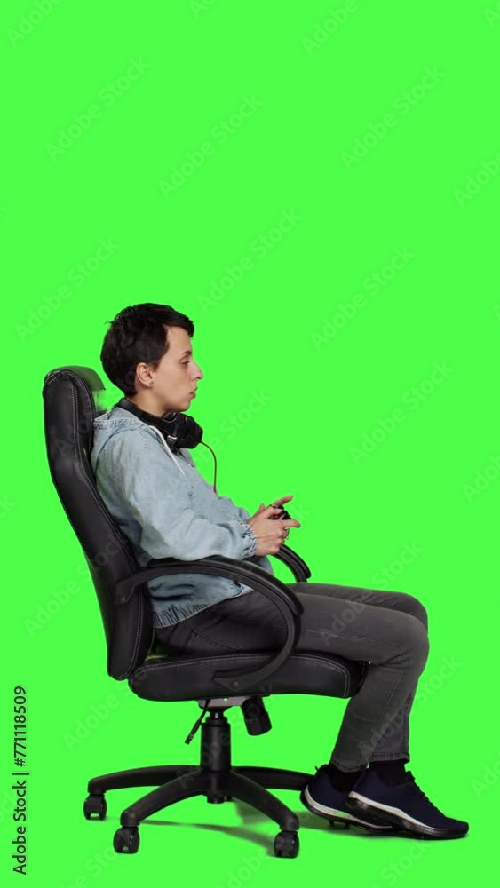 Profile Woman gamer playing online video games with controller, sitting in an office chair against greenscreen backdrop. Joyful person having fun with e sport competition, modern gaming setup. Camera Profile Woman gamer playing online video games with controller, sitting in an office chair against greenscreen backdrop. Joyful person having fun with e sport competition, modern gaming setup. Camera