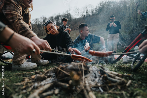 Group of friends grilling sausages over an open fire during a relaxing outdoor barbecue gathering in nature. photo
