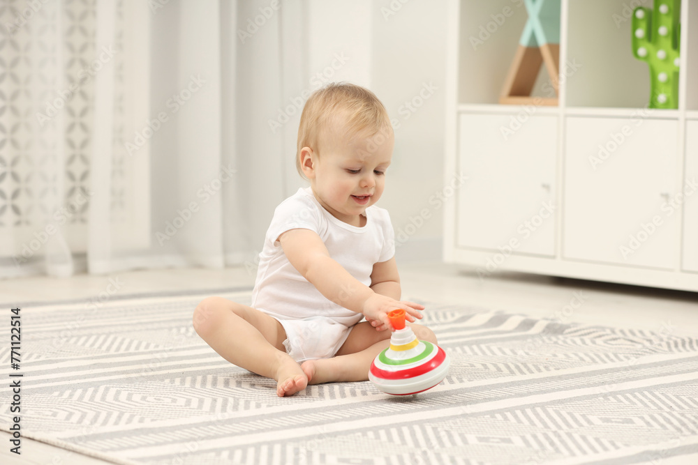 Children toys. Cute little boy playing with spinning top on rug at home Children toys. Cute little boy playing with spinning top on rug at home