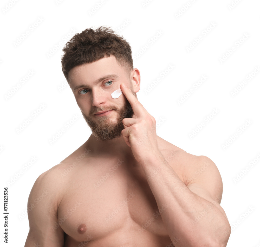 Fototapeta premium Handsome man applying moisturizing cream onto his face on white background