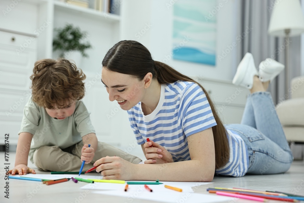 Mother and her little son drawing with colorful markers on floor at home Mother and her little son drawing with colorful markers on floor at home