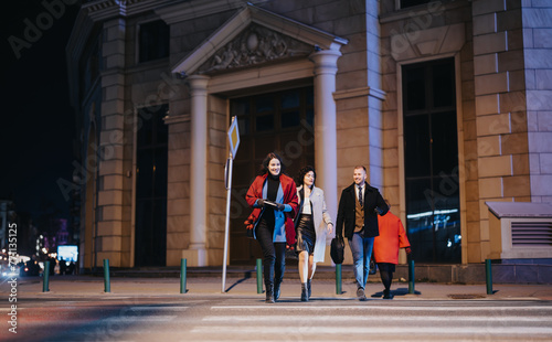 A dynamic scene of four friends casually strolling through a brightly lit city street at night, evoking feelings of freedom and companionship.