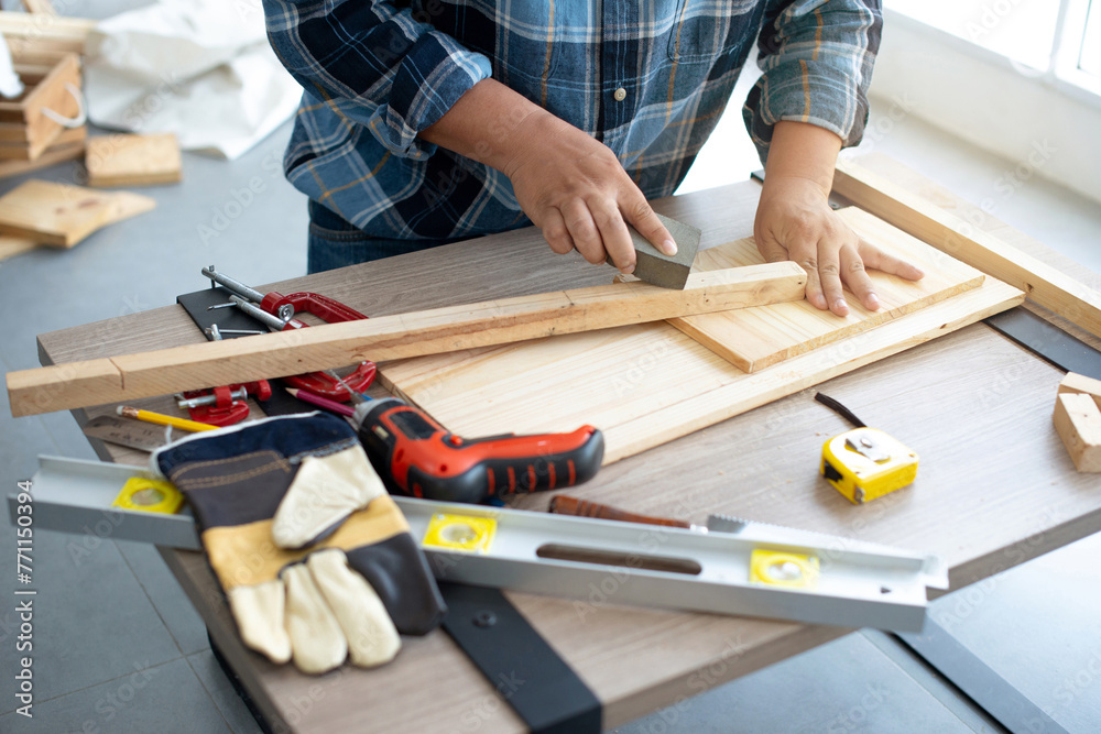 Male carpenter hands at work with sand paper, carpenter doing his job in carpentry workshop Male carpenter hands at work with sand paper, carpenter doing his job in carpentry workshop