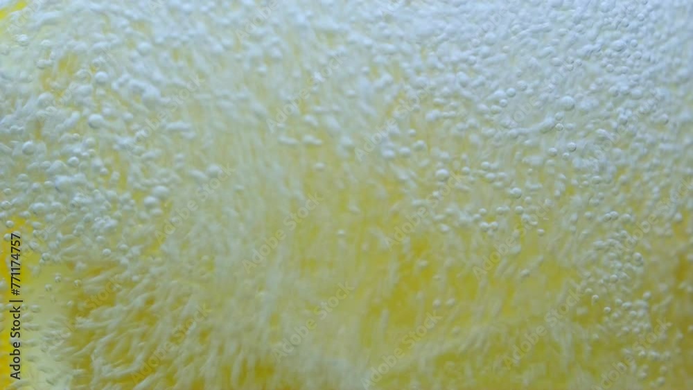 A slice of lemon falls into a glass of water. Slow motion. Close up. Lemon slice and ice cube falling down in water with glass. macro. Fruit citrus cocktail close-up texture, The bubbles are bubbling