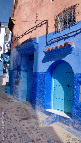 Blue, wooden door in a blue wall in the medina, in Chefchaouen, Morocco © Angela