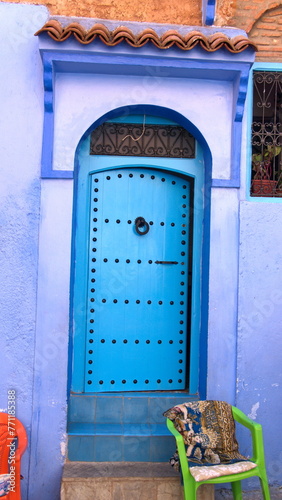 Blue, wooden door in a blue wall in the medina, in Chefchaouen, Morocco © Angela