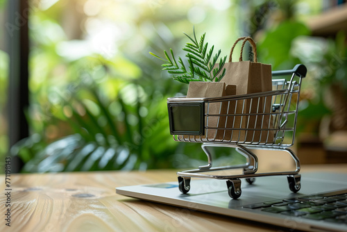 A miniature shopping cart filled with paper bags and greenery, placed on a laptop keyboard, symbolizing eco-friendly online shopping. photo