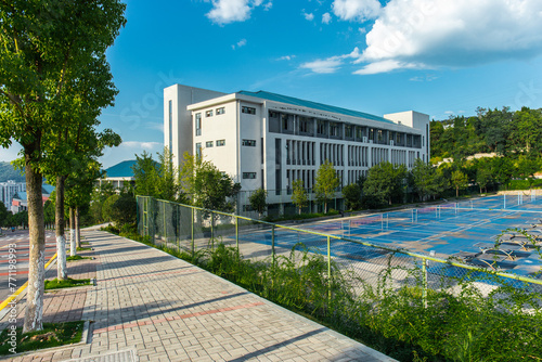 In the quiet and uninhabited university campus, there is a tennis court outside a teaching building on a sunny summer day © 宗毅
