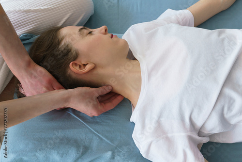 young masseuse does a Thai massage on the floor massaging her neck and shoulders