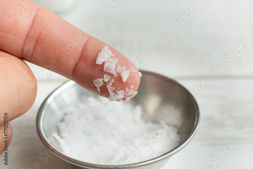 A view of large sea salt crystals on the tip of a finger.