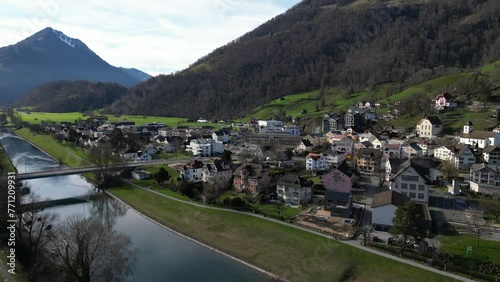 Drone clip of calm river with bridge, and mountainous village of Weesen, St Gallen, Switzerland photo