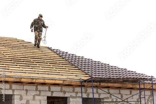 Workers install tiles on the roof of a house in winter