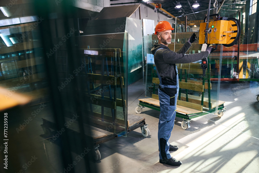 Male using a vacuum lifting device in a window factory Male using a vacuum lifting device in a window factory
