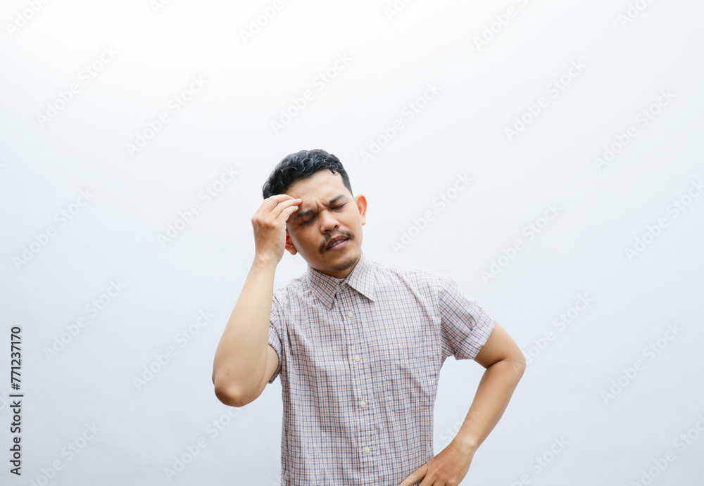 an asian man shows a dizzy expression and holds his head an asian man shows a dizzy expression and holds his head