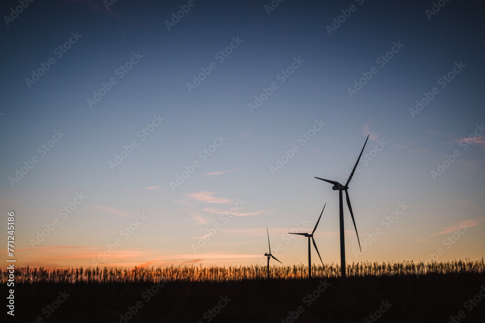 Three windmills making clean energy in a field in Iowa at sunrise